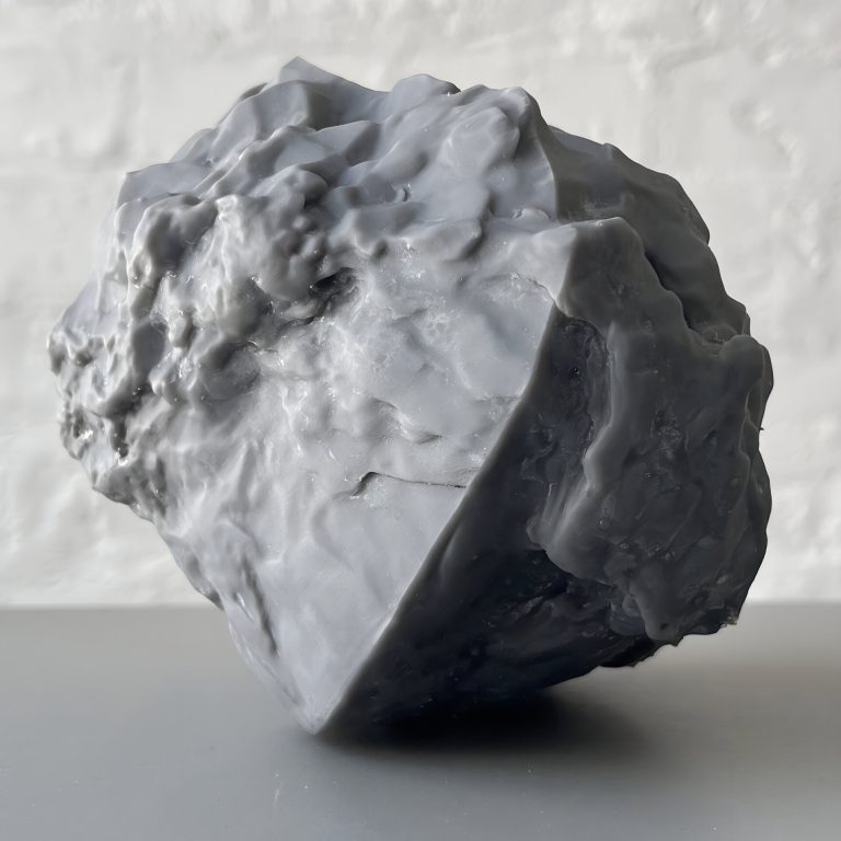 A 3d printed resin object sits on a surface with a rough, sand grain topology.