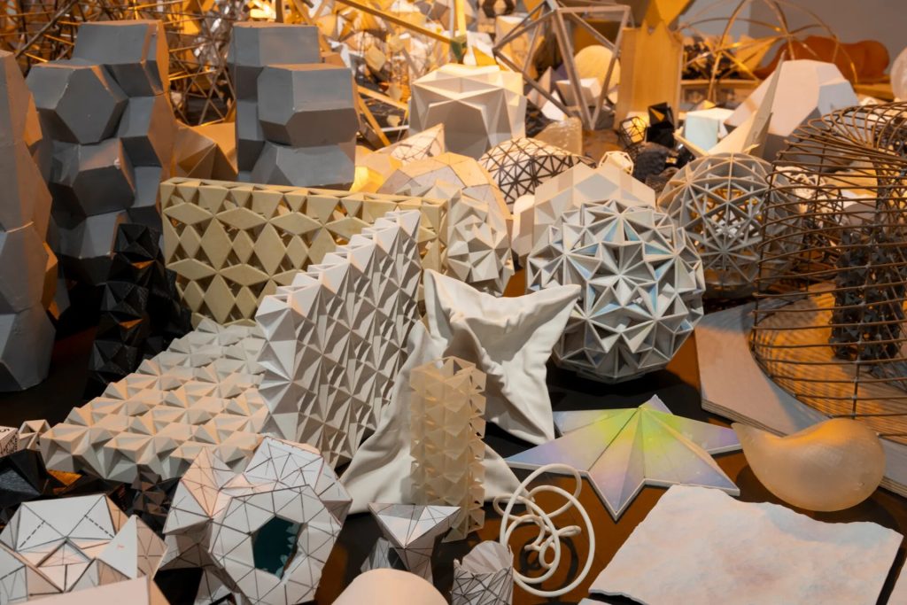 Geometric maquettes and prototypes sit on a circular table in Studio Olafur Eliasson's installation.