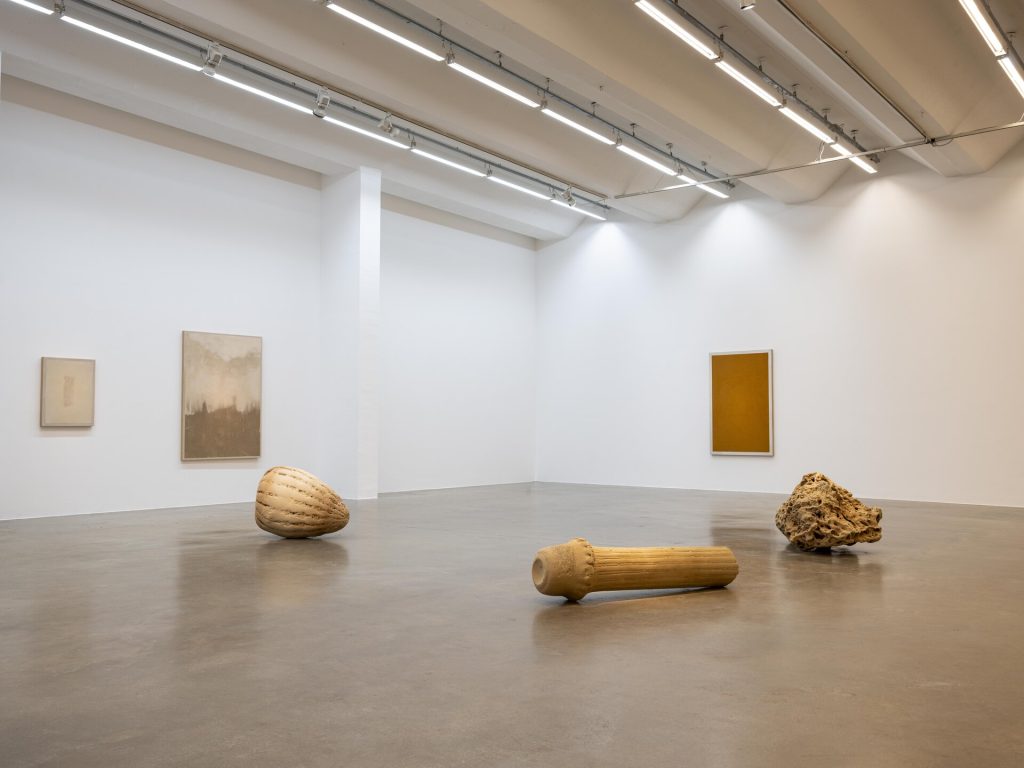 Three 3D printed sand sculptures sit on the floor while sand paintings hang on the gallery walls.