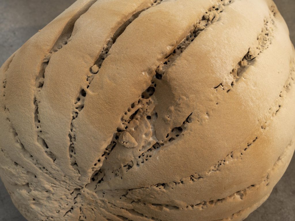 A 3D-printed sand sphere has deep grooves and porous holes on its surface.