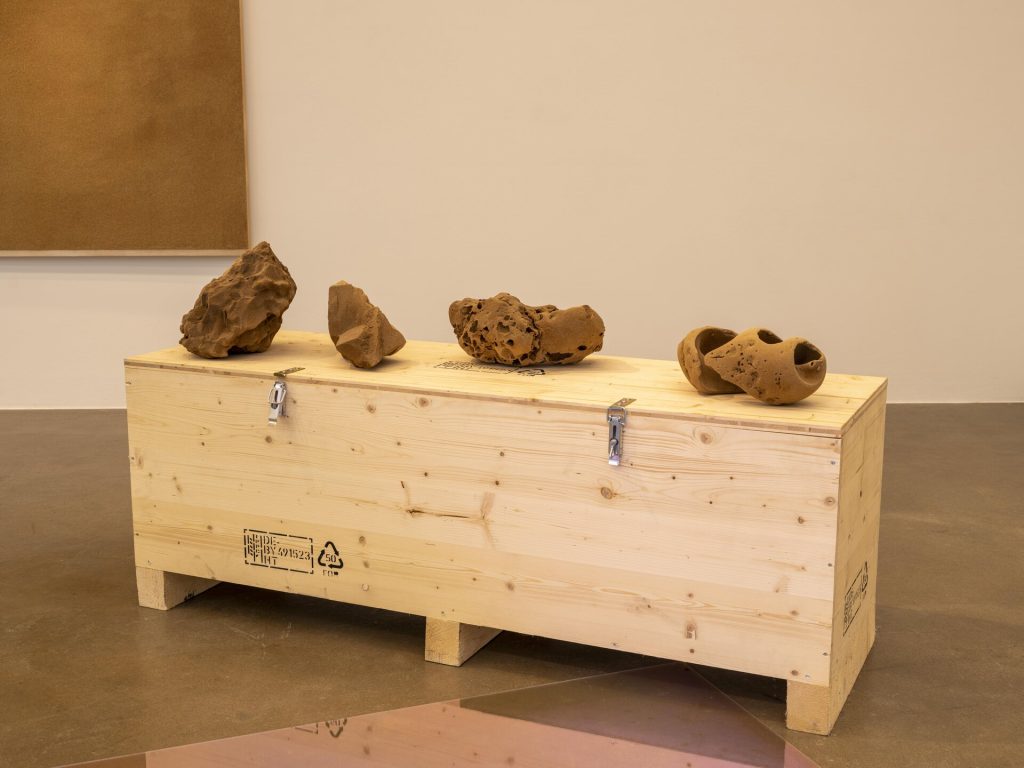 Four 3D printed sand sculptures sit on a wooden crate.