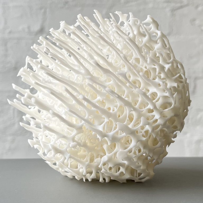 A white 3d printed resin sphere has a porous lattice structure with protruding spikes.