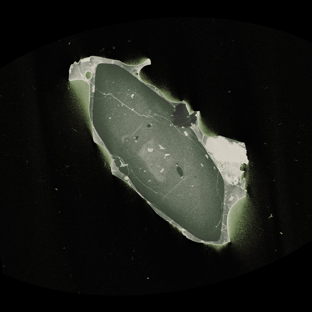 A green-tinted nano-CT cross-section of a sand grain with internal voids sits on a black background.